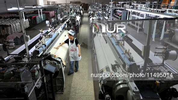 A female textile worker is working at a jacquard loom workshop at Jiangsu Hengyuan Silk Group located in the high-tech zone in Hai 'an, Jian...