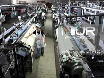 A female textile worker is working at a jacquard loom workshop at Jiangsu Hengyuan Silk Group located in the high-tech zone in Hai 'an, Jian...