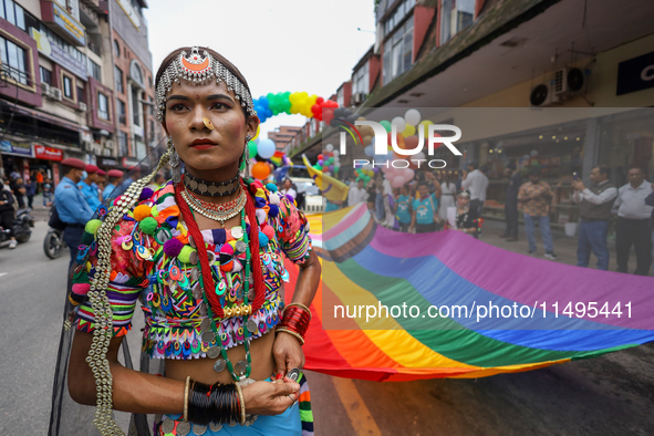 A member of the sexual minority LGBTIQ+ group of Nepal is holding the edge of a rainbow flag during the Gaijatra (Pride) parade in Kathmandu...