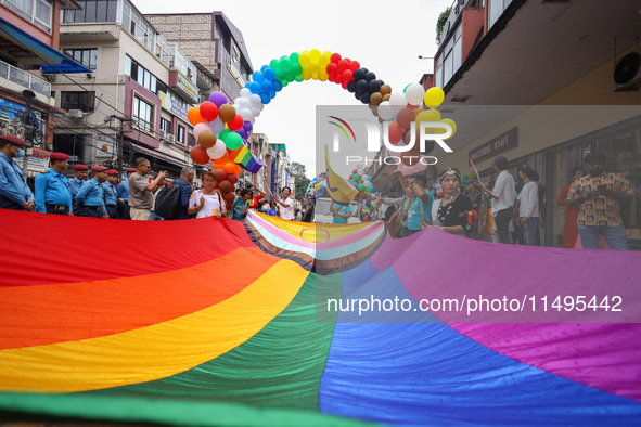 Members of the sexual minority LGBTIQ+ group of Nepal are unfurling the rainbow flag, holding its edges before the formal start of the Gaija...