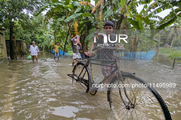 Bangladeshi people suffer from floods during heavy monsoon rains in rural Bangladesh on August 20, 2024. 