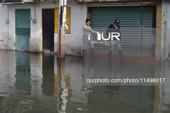 People are trying to walk on flooded streets in Chalco, State of Mexico, on August 20, 2024, where several families are being severely affec...