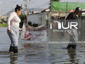 People are trying to walk on flooded streets in Chalco, State of Mexico, on August 20, 2024, where several families are being severely affec...