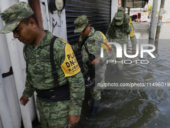 Members of the Mexican army are trying to walk on flooded streets in Chalco, State of Mexico, on August 20, 2024, where several families are...