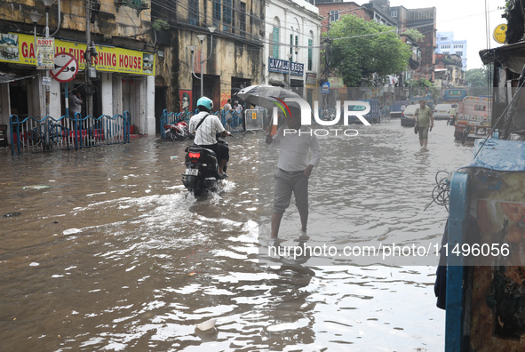 Commuters are walking on a busy water-logged street after heavy monsoon rain in Kolkata, India, on August 20, 2024. 