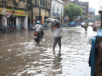 Commuters are walking on a busy water-logged street after heavy monsoon rain in Kolkata, India, on August 20, 2024. (