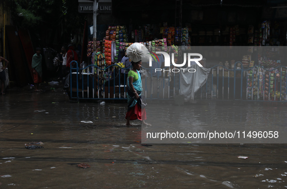 A woman is walking on a busy water-logged street after heavy monsoon rain in Kolkata, India, on August 20, 2024. 