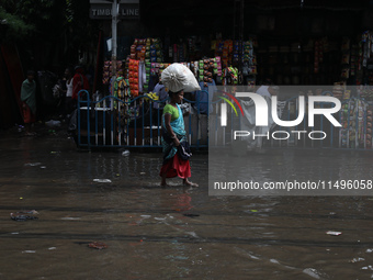 A woman is walking on a busy water-logged street after heavy monsoon rain in Kolkata, India, on August 20, 2024. (