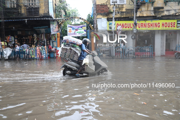 A man is riding his two-wheeler through a water-logged street after heavy monsoon rain in Kolkata, India, on August 20, 2024. 