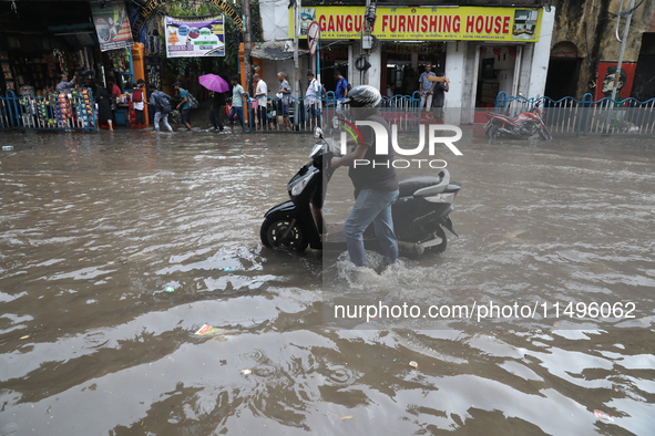 A man is pushing   two-wheeler through a water-logged street after heavy during monsoon rain in Kolkata, India, on August 20, 2024. 