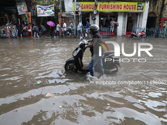 A man is pushing   two-wheeler through a water-logged street after heavy during monsoon rain in Kolkata, India, on August 20, 2024. (