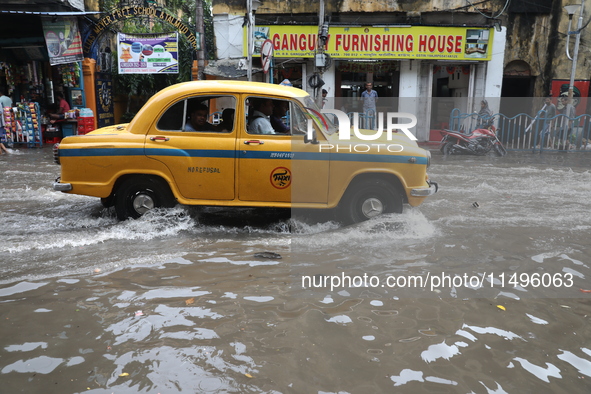 A taxi is driving through a water-logged street after heavy monsoon rain in Kolkata, India, on August 20, 2024. 