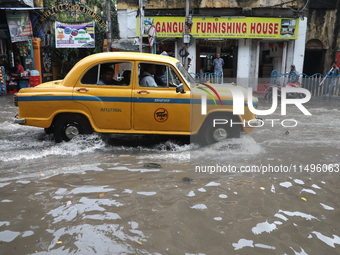 A taxi is driving through a water-logged street after heavy monsoon rain in Kolkata, India, on August 20, 2024. (