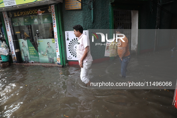 A man is walking beside a water-logged street after heavy monsoon rain in Kolkata, India, on August 20, 2024. 