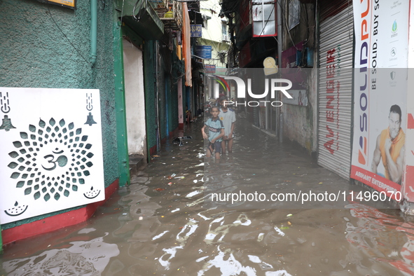 Children are walking beside a water-logged street after heavy monsoon rain in Kolkata, India, on August 20, 2024. 