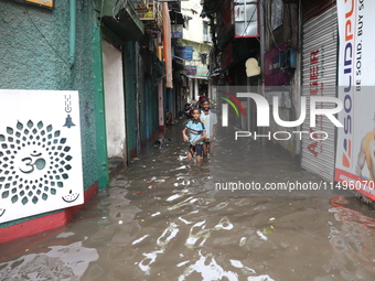 Children are walking beside a water-logged street after heavy monsoon rain in Kolkata, India, on August 20, 2024. (