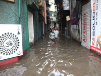 Children are walking beside a water-logged street after heavy monsoon rain in Kolkata, India, on August 20, 2024. (