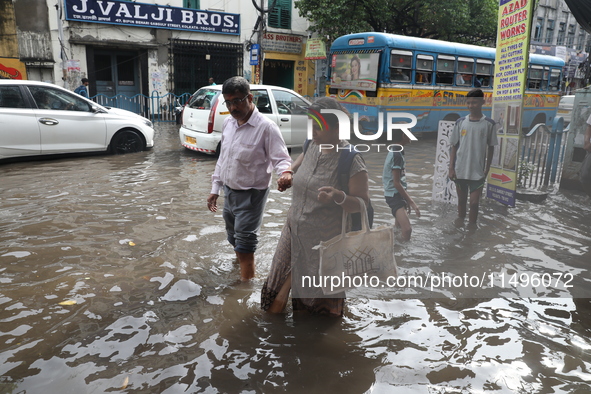 Commuters are walking on a busy water-logged street after heavy monsoon rain in Kolkata, India, on August 20, 2024. 