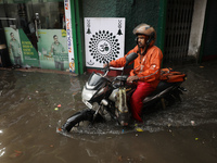 A food delivery person is riding his bike beside a water-logged street after heavy monsoon rain in Kolkata, India, on August 20, 2024. (