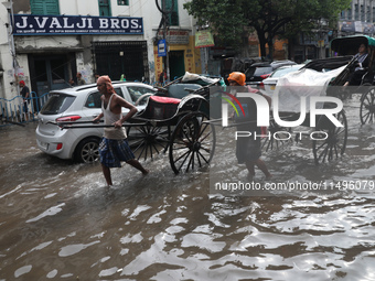 Rickshaw pullers are making their way through a water-logged street after heavy monsoon rain in Kolkata, India, on August 20, 2024. (