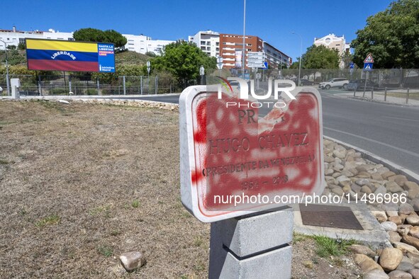 A vandalized stone plate with the words Plaza Hugo Chavez, President of Venezuela, is being seen near a billboard with the Spanish inscripti...