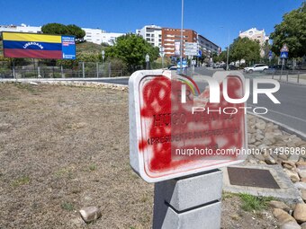 A vandalized stone plate with the words Plaza Hugo Chavez, President of Venezuela, is being seen near a billboard with the Spanish inscripti...