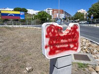 A vandalized stone plate with the words Plaza Hugo Chavez, President of Venezuela, is being seen near a billboard with the Spanish inscripti...