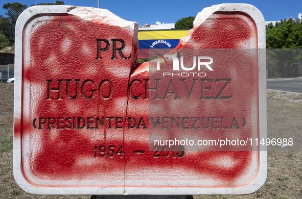 A vandalized stone plate with the words Plaza Hugo Chavez, President of Venezuela, is being seen near a billboard with the Spanish inscripti...