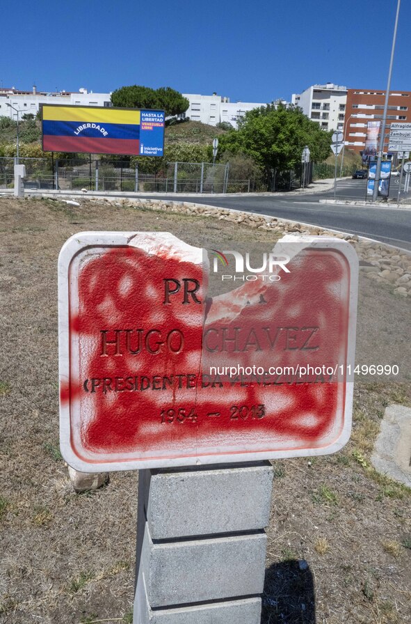 A vandalized stone plate with the words Plaza Hugo Chavez, President of Venezuela, is being seen near a billboard with the Spanish inscripti...