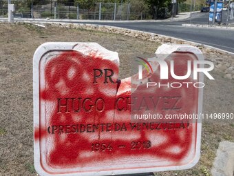 A vandalized stone plate with the words Plaza Hugo Chavez, President of Venezuela, is being seen near a billboard with the Spanish inscripti...