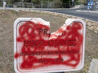 A vandalized stone plate with the words Plaza Hugo Chavez, President of Venezuela, is being seen near a billboard with the Spanish inscripti...