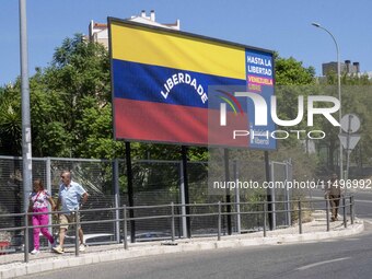 Two people are walking near a billboard with the inscription in Spanish ''Venezuela Libre'' (free Venezuela) in the center of Lisbon, Portug...