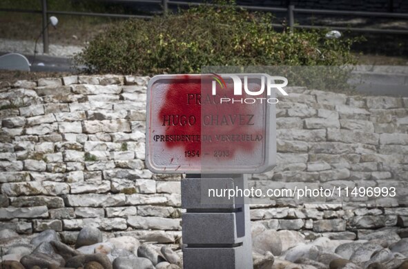 A vandalized stone plate with the words Plaza Hugo Chavez, President of Venezuela, is being seen near a billboard with the Spanish inscripti...