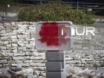 A vandalized stone plate with the words Plaza Hugo Chavez, President of Venezuela, is being seen near a billboard with the Spanish inscripti...