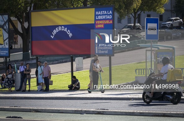 Several people are standing near a billboard with the inscription in Spanish ''Venezuela Libre'' (free Venezuela) in central Lisbon, Portuga...