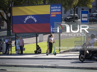 Several people are standing near a billboard with the inscription in Spanish ''Venezuela Libre'' (free Venezuela) in central Lisbon, Portuga...