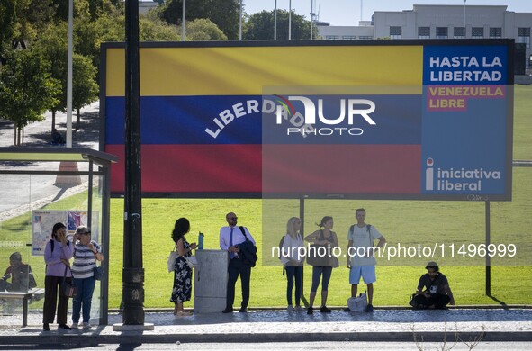 Several people are standing near a billboard with the inscription in Spanish ''Venezuela Libre'' (free Venezuela) in central Lisbon, Portuga...