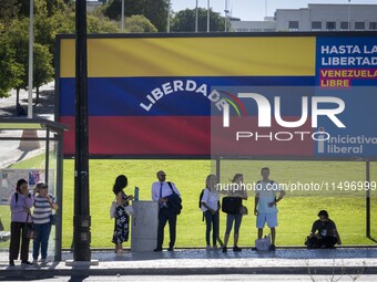 Several people are standing near a billboard with the inscription in Spanish ''Venezuela Libre'' (free Venezuela) in central Lisbon, Portuga...