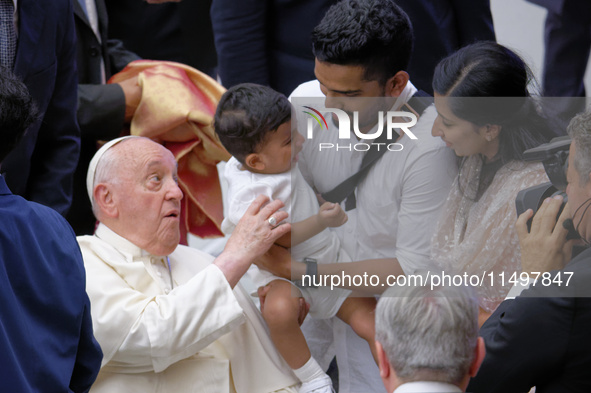 Pope Francis meets a family during the weekly general audience at the Vatican on August 21, 2024. 