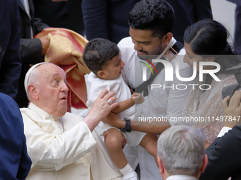 Pope Francis meets a family during the weekly general audience at the Vatican on August 21, 2024. (