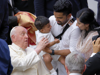 Pope Francis meets a family during the weekly general audience at the Vatican on August 21, 2024. (