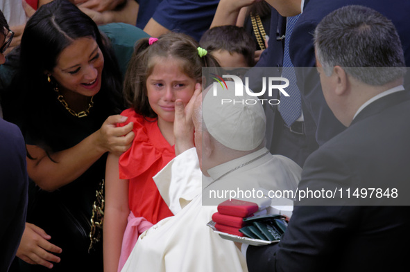 Pope Francis comforts a little girl as she cries at the end of the weekly general audience in The Vatican, on August 21, 2024, at Paul-VI ha...