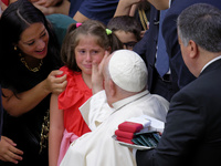 Pope Francis comforts a little girl as she cries at the end of the weekly general audience in The Vatican, on August 21, 2024, at Paul-VI ha...