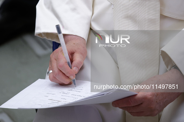 Pope Francis signs a paper at the end of the weekly general audience in The Vatican, on August 21, 2024, at Paul-VI hall. 