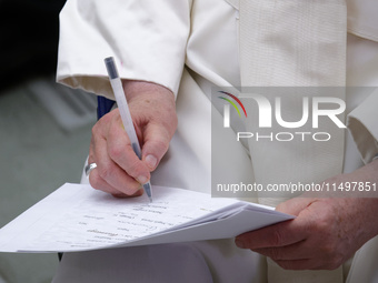 Pope Francis signs a paper at the end of the weekly general audience in The Vatican, on August 21, 2024, at Paul-VI hall. (