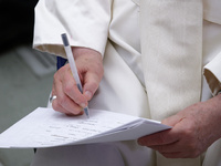 Pope Francis signs a paper at the end of the weekly general audience in The Vatican, on August 21, 2024, at Paul-VI hall. (