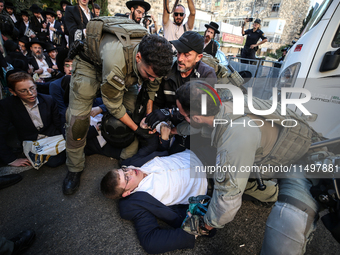 Israeli police officers intervene in Ultra-Orthodox Jews, also known as Haredim, who gather to stage a protest against mandatory military se...