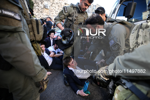 Israeli police officers intervene in Ultra-Orthodox Jews, also known as Haredim, who gather to stage a protest against mandatory military se...