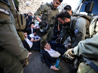 Israeli police officers intervene in Ultra-Orthodox Jews, also known as Haredim, who gather to stage a protest against mandatory military se...