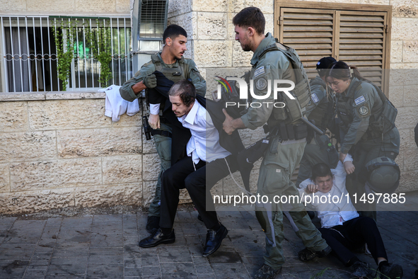 Israeli police officers intervene in Ultra-Orthodox Jews, also known as Haredim, who gather to stage a protest against mandatory military se...